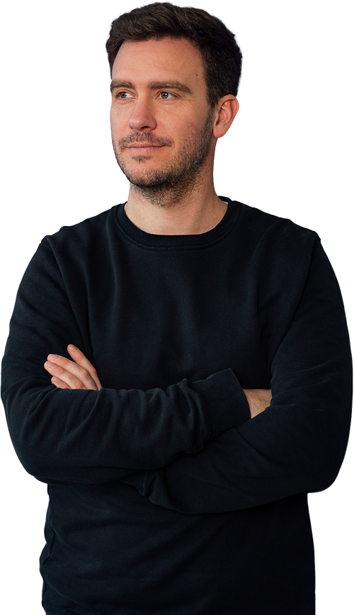 Philipp Kaiser im dunklen Pullover mit verschränkten Armen, leicht lächelnd zur Seite blickend